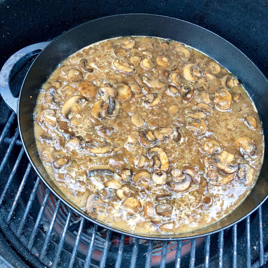 mushroom sauce in a cast iron on the grill.