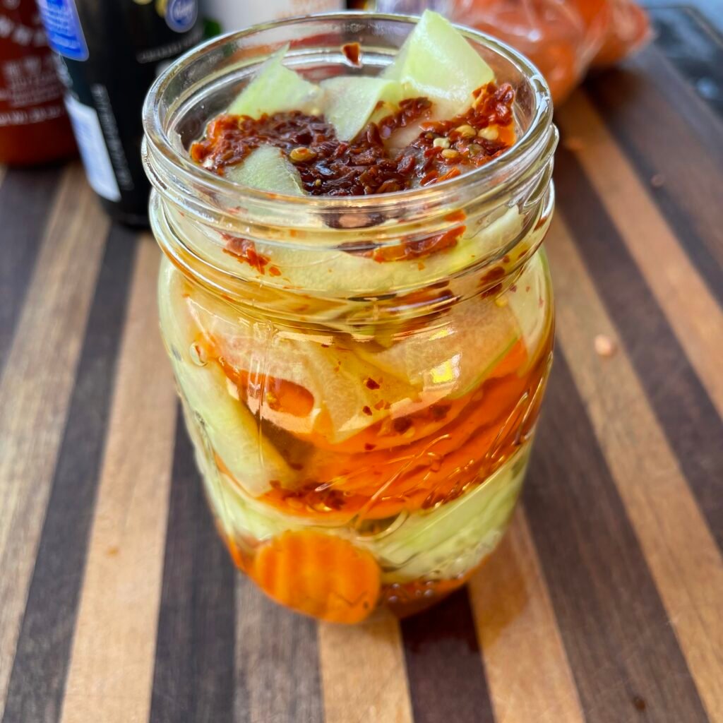 mason jar with carrot and cucumber pieces and pickling brine. 