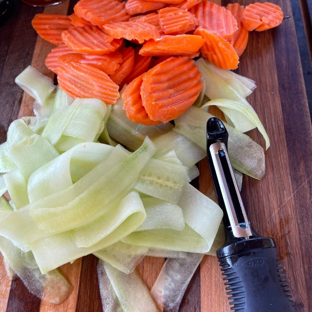 sliced cucumber and carrots on cutting board. 