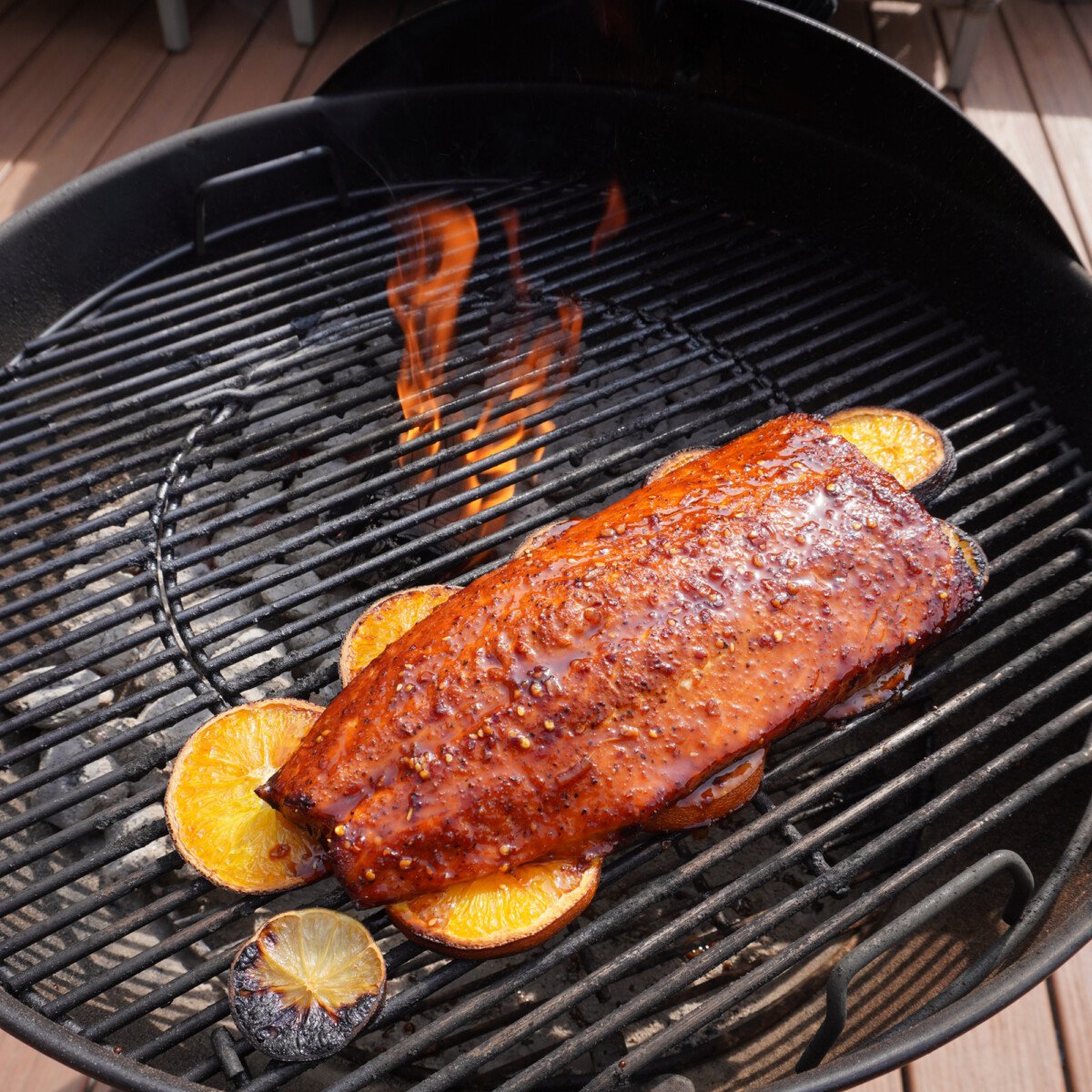 citrus salmon cooked on the grill on a bed of sliced oranges and  limes.