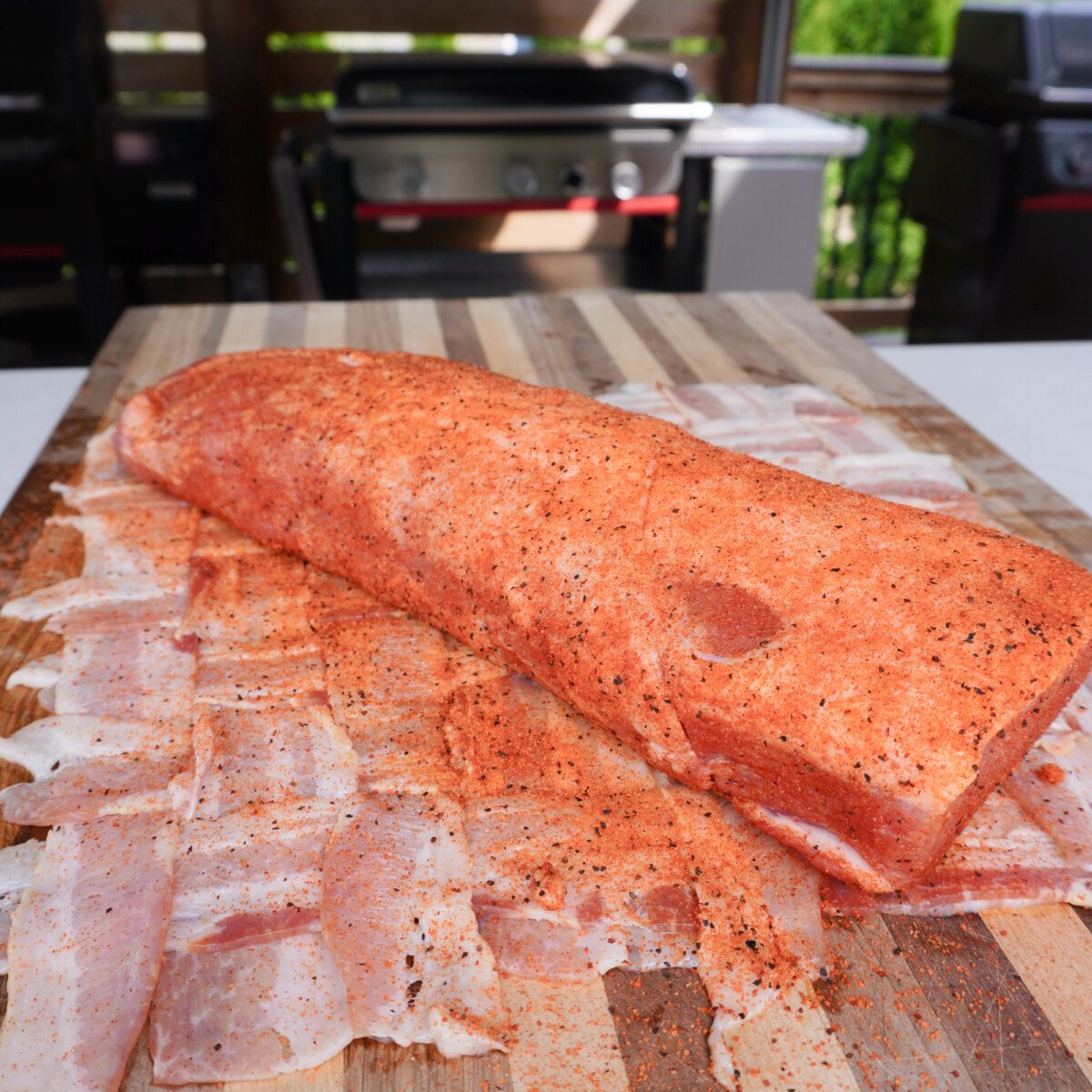 Seasoned pork loin on top of a raw bacon weave.