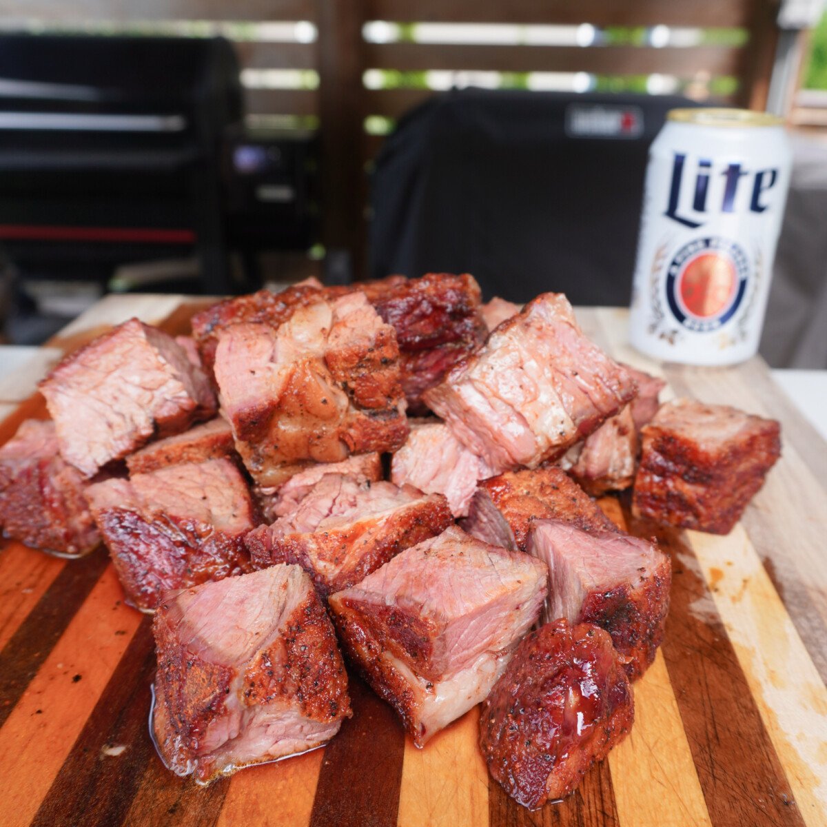 smoked chuck roast cubed on a cutting board with a can of beer.