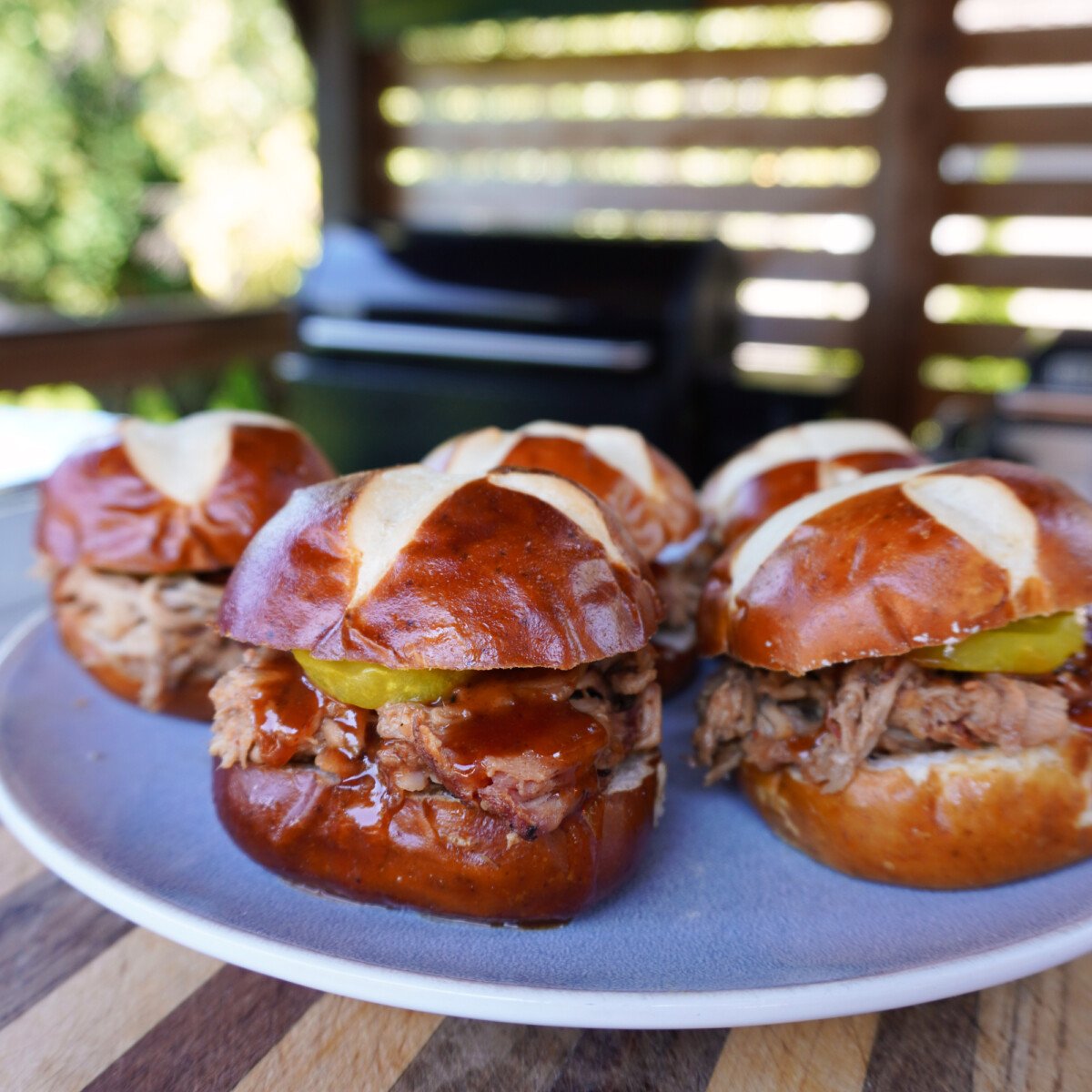 Smoked Pulled Pork with Mustard BBQ Sauce sandwiches on pretzel buns.