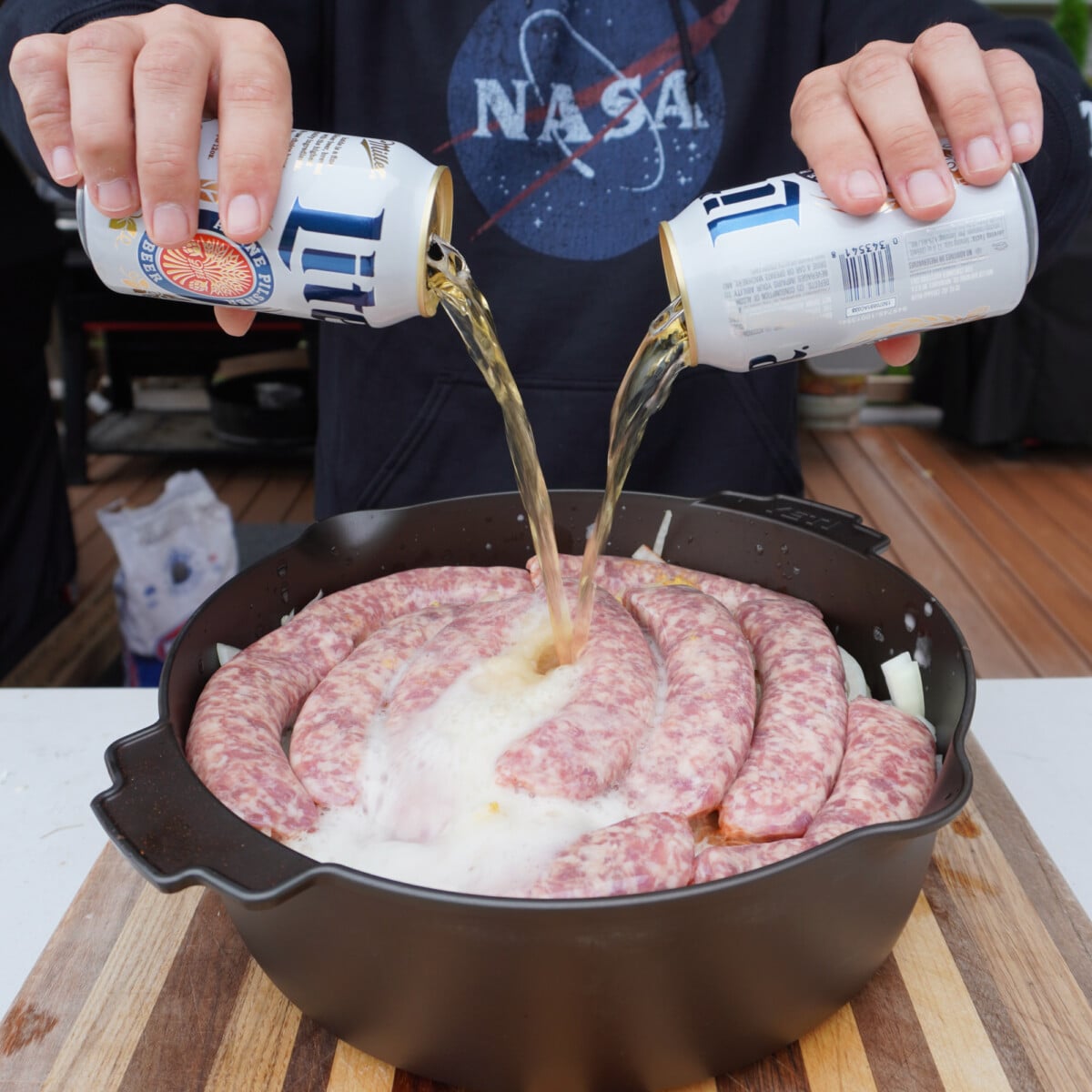 beer poured into dutch oven filled with onions and bratwurst.