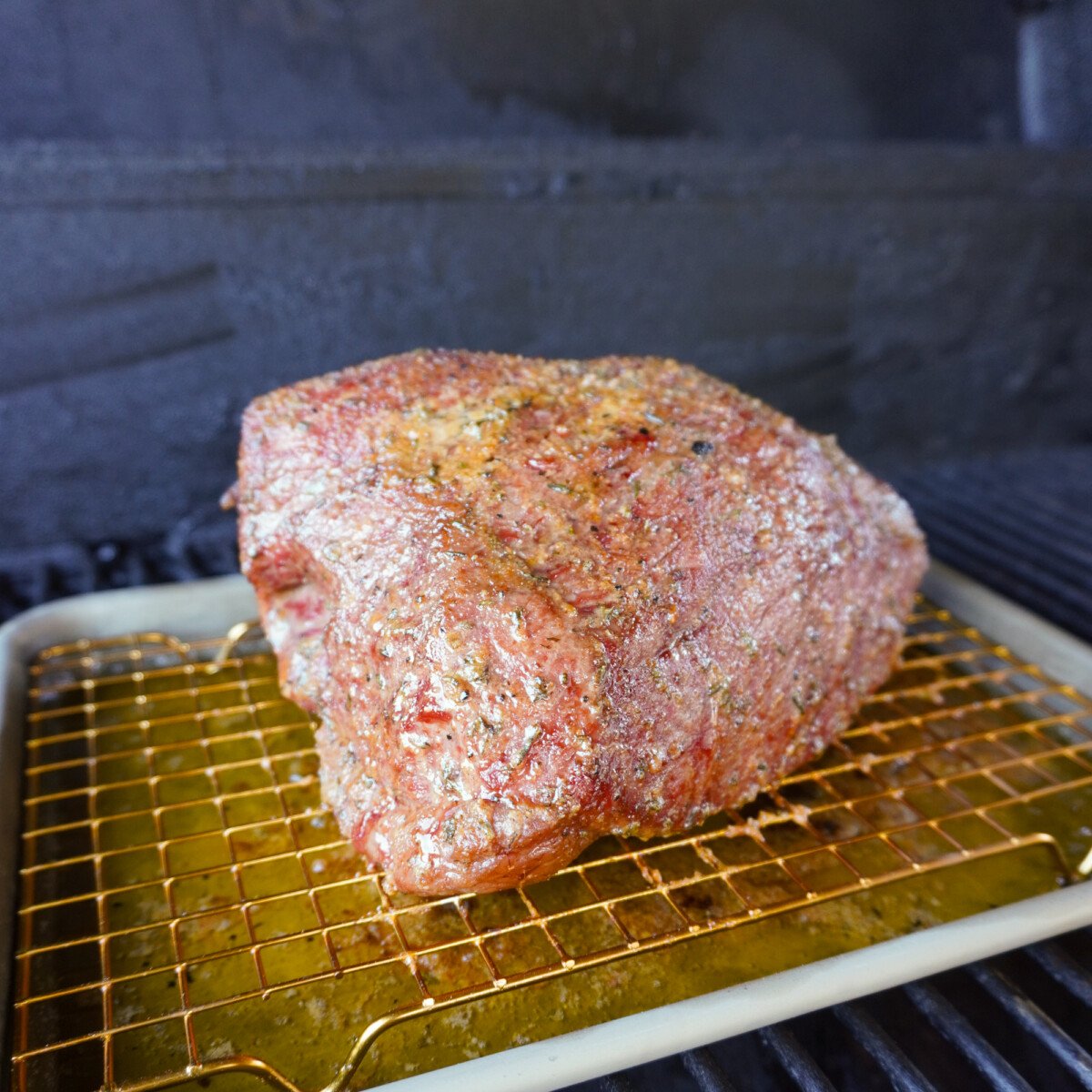 Garlic and Herb beef in a smoker on a wire rack.