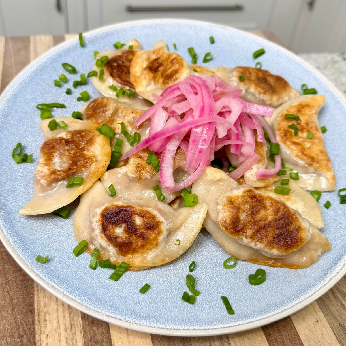 pulled pork pierogi placed with pickled red onion on top.
