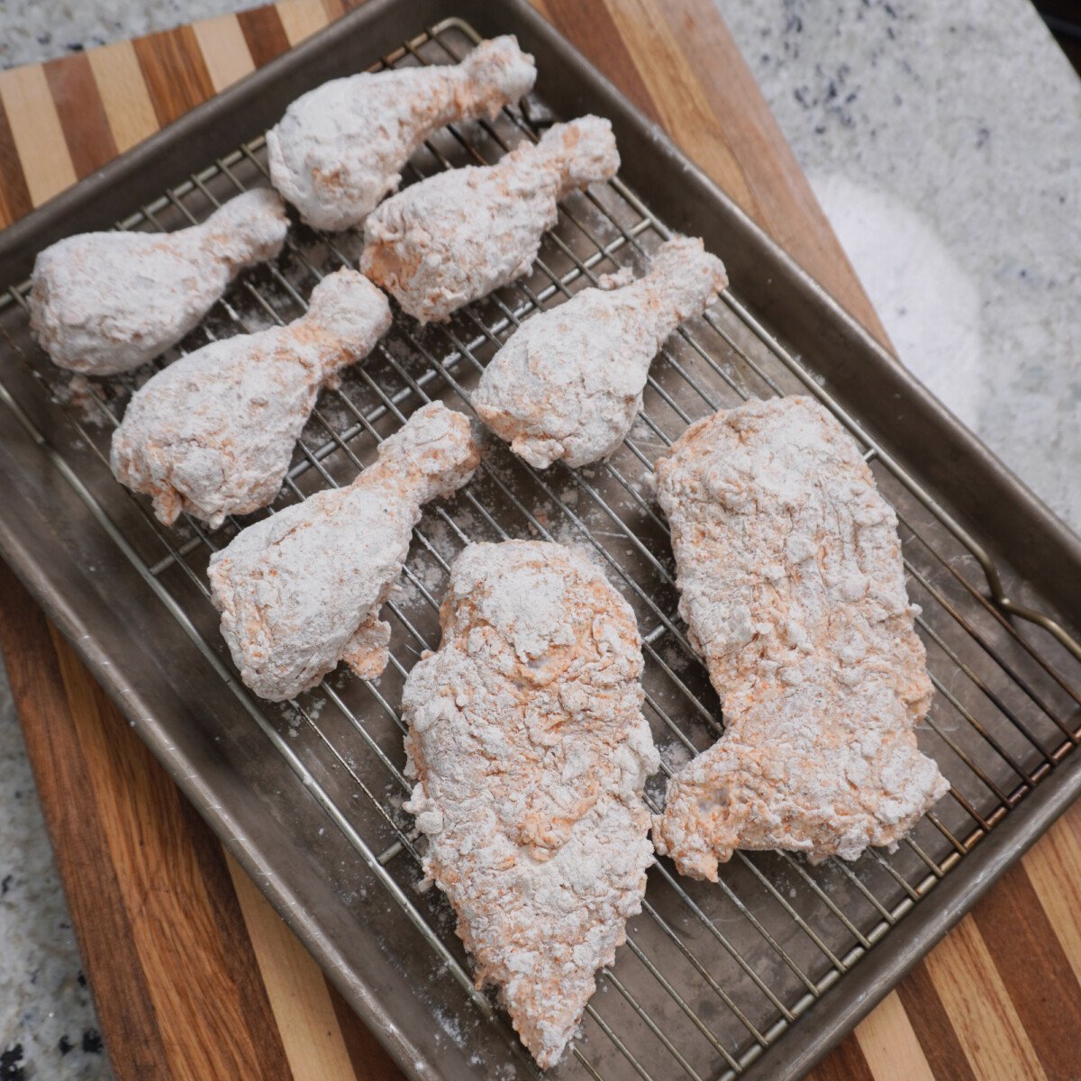 Coated chicken on a wire rack ready to be fried.