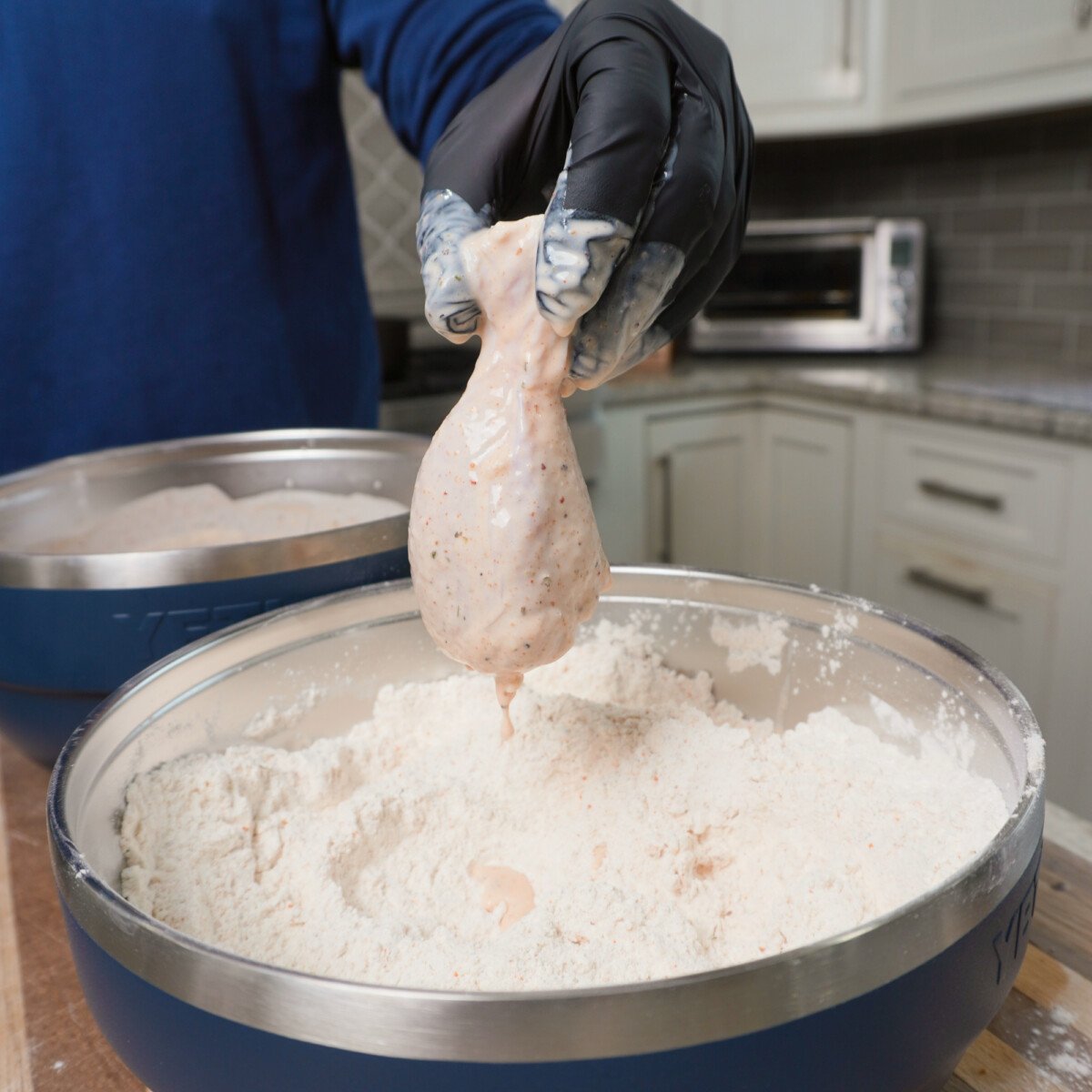 buttermilk brined chicken drumstick above a flour coating for the best crispy fried chicken.