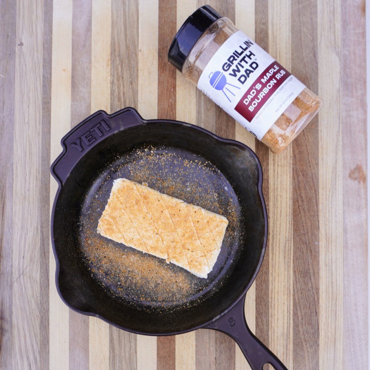 seasoned and scored cream cheese block in a cast iron skillet.