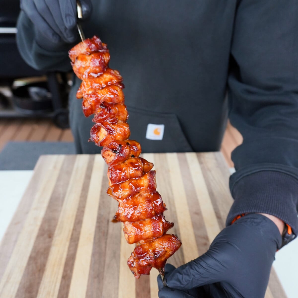 presenting grilled bacon wrapped chicken skewer.