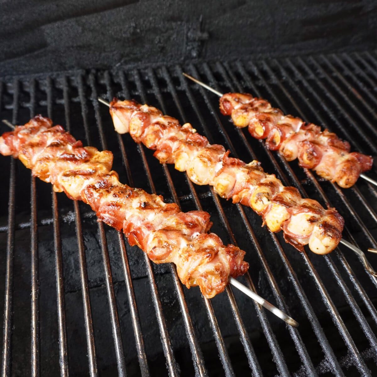Bacon wrapped chicken skewers on the grill.