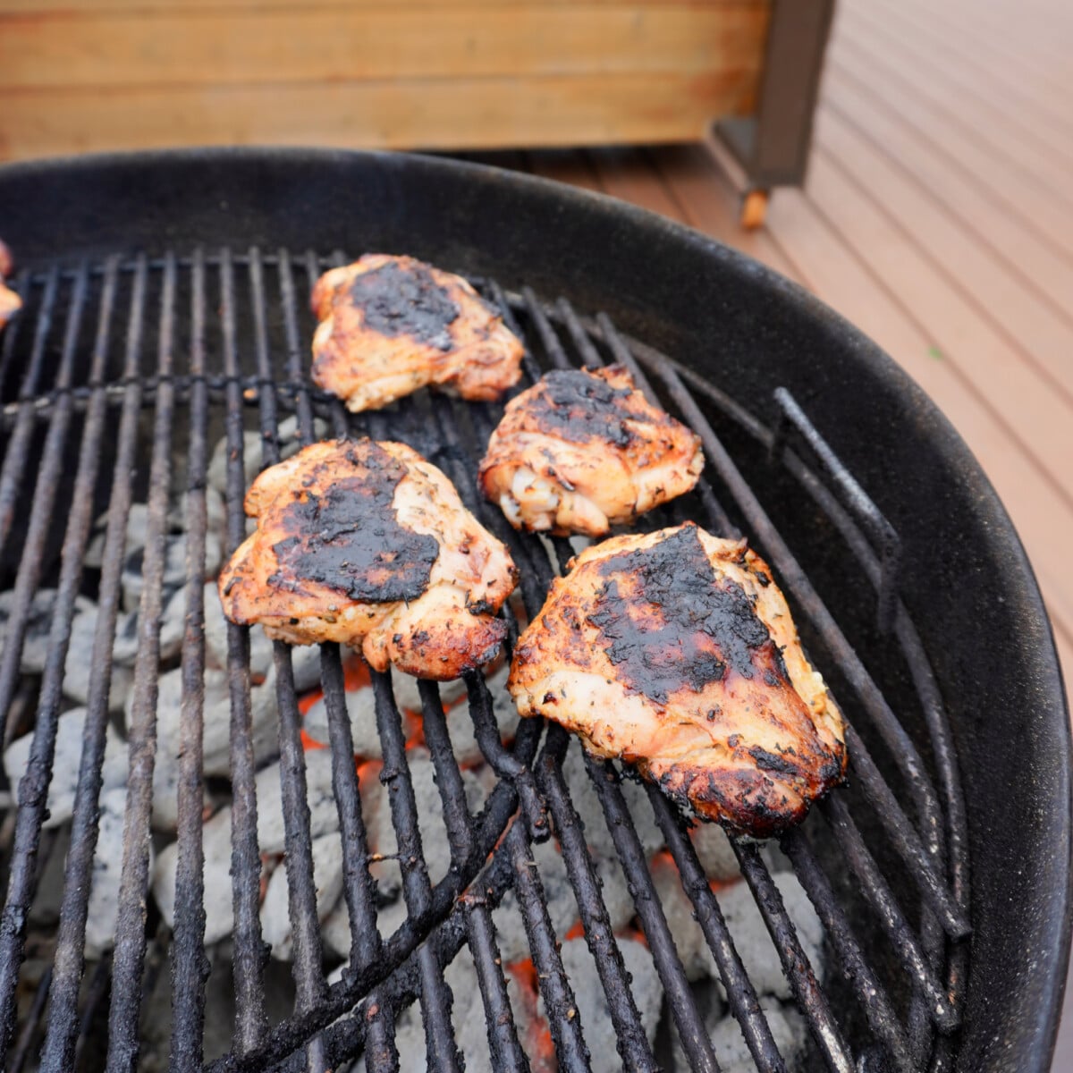 Grilled and seared chicken thighs on the direct side of a charcoal grill.