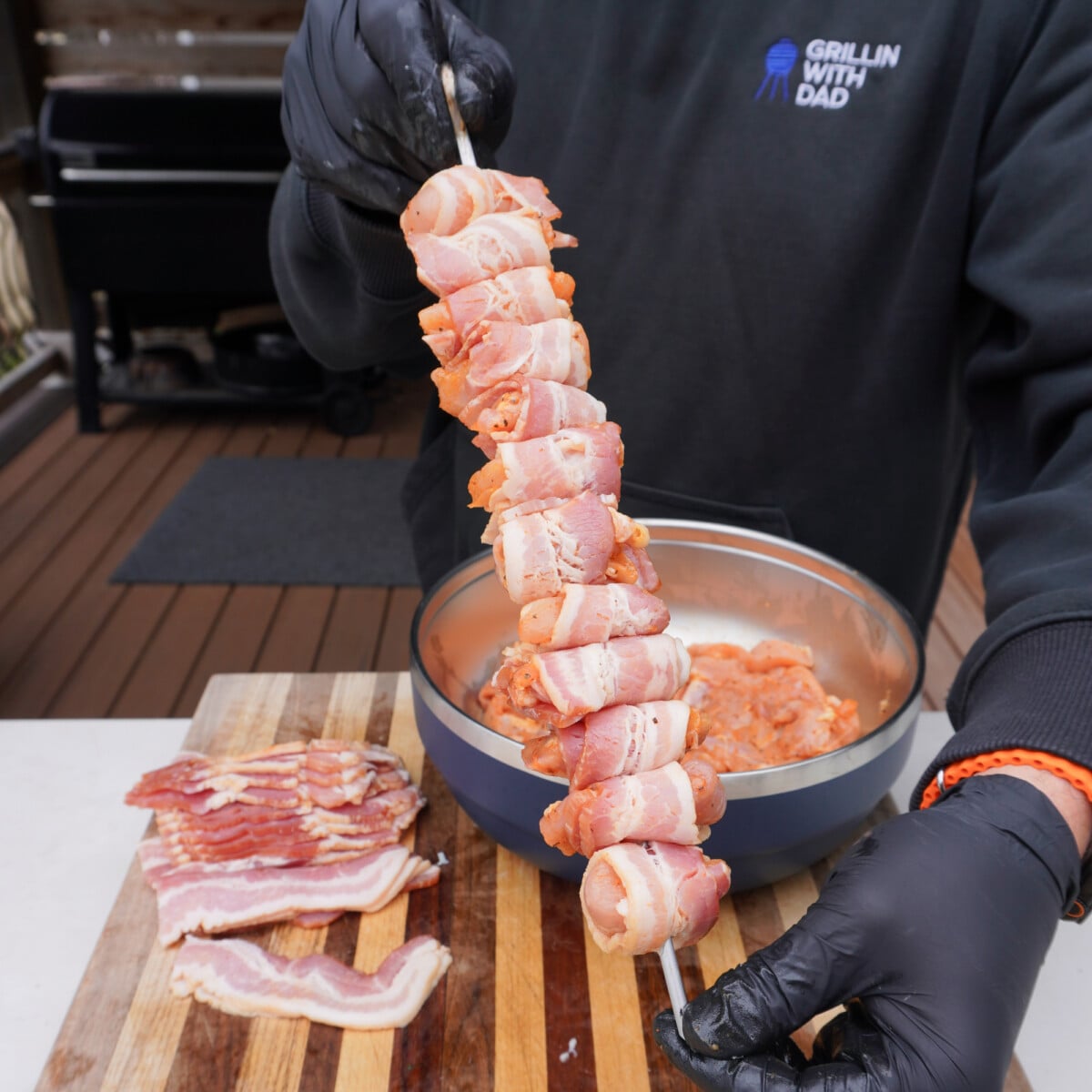 Skewered raw chicken wrapped in bacon bites.