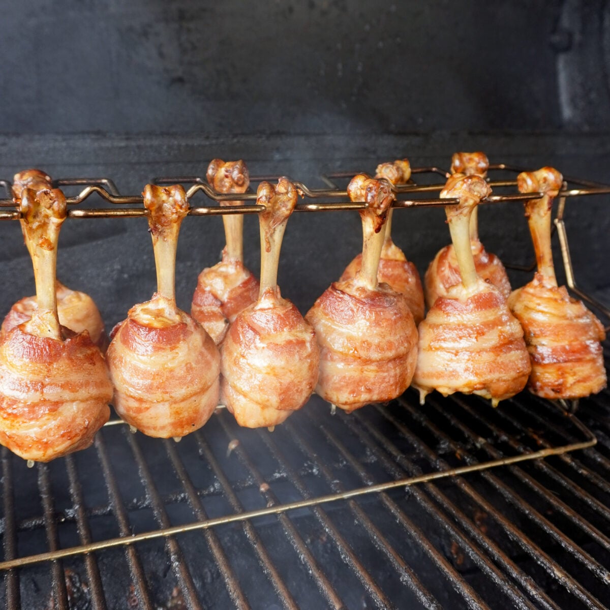 grilled bacon wrapped chicken drumsticks on the smoker.