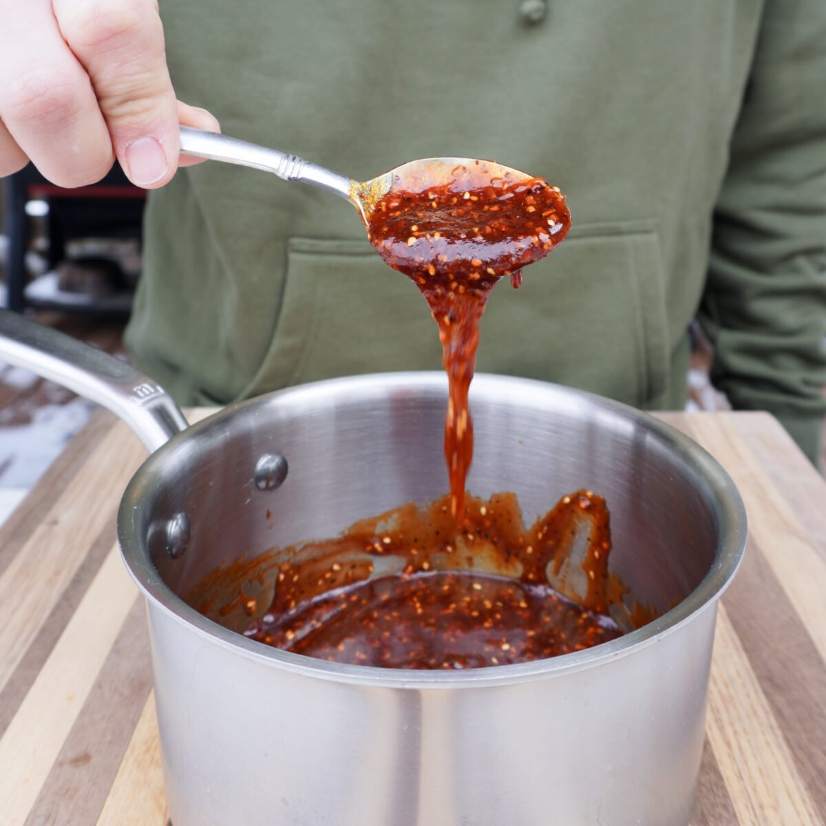 Chili Crunch Honey BBQ Sauce spooned in a saucepan.