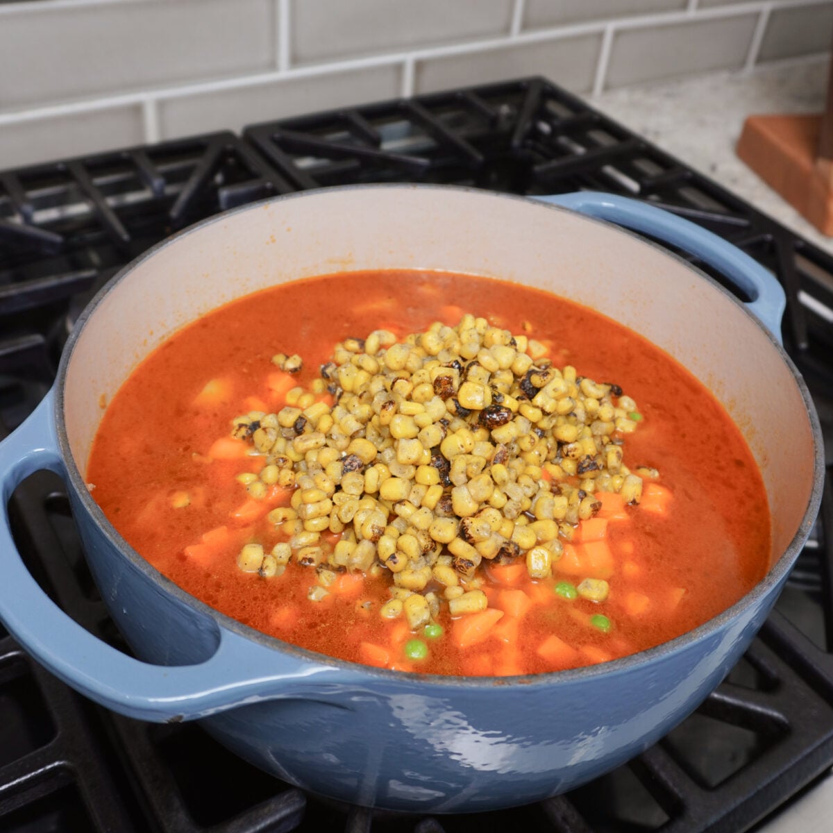 Adding veggies to the hearty cowboy soup.