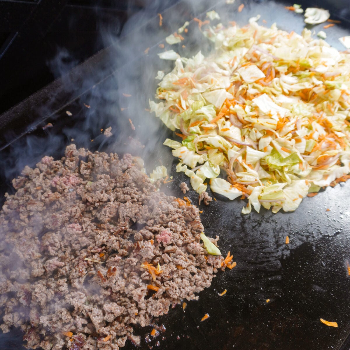 cooked ground beef and veggies on griddle.