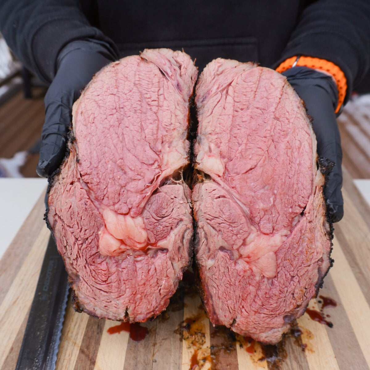 Grilled and seared prime rib sliced in half showing a medium rare cook inside.