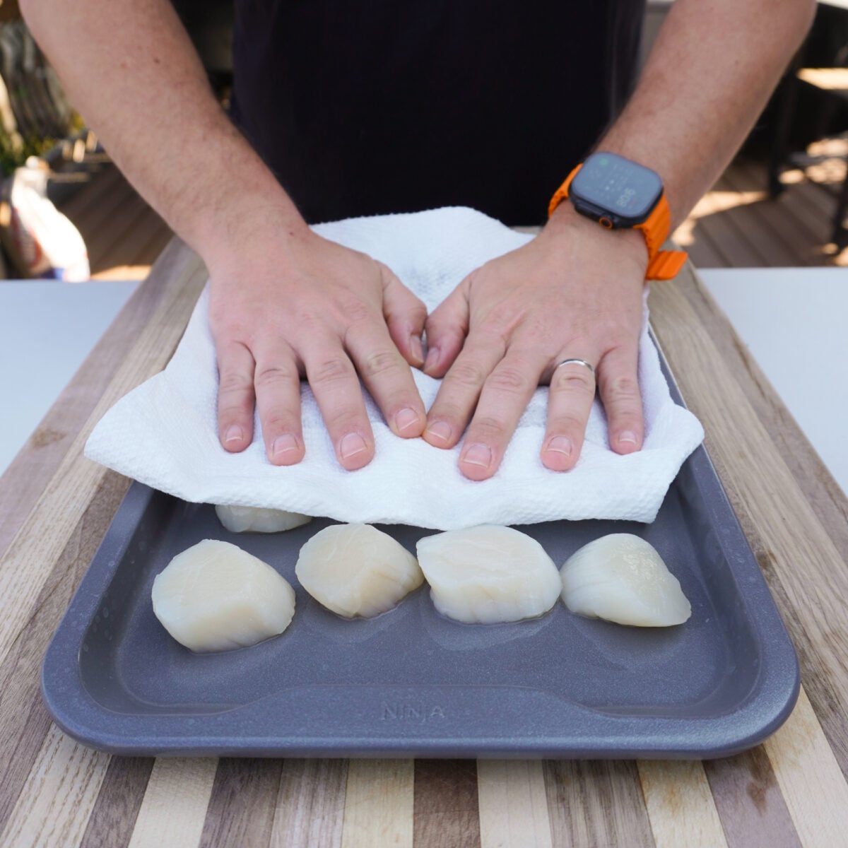 patting dry raw defrosted scallops.