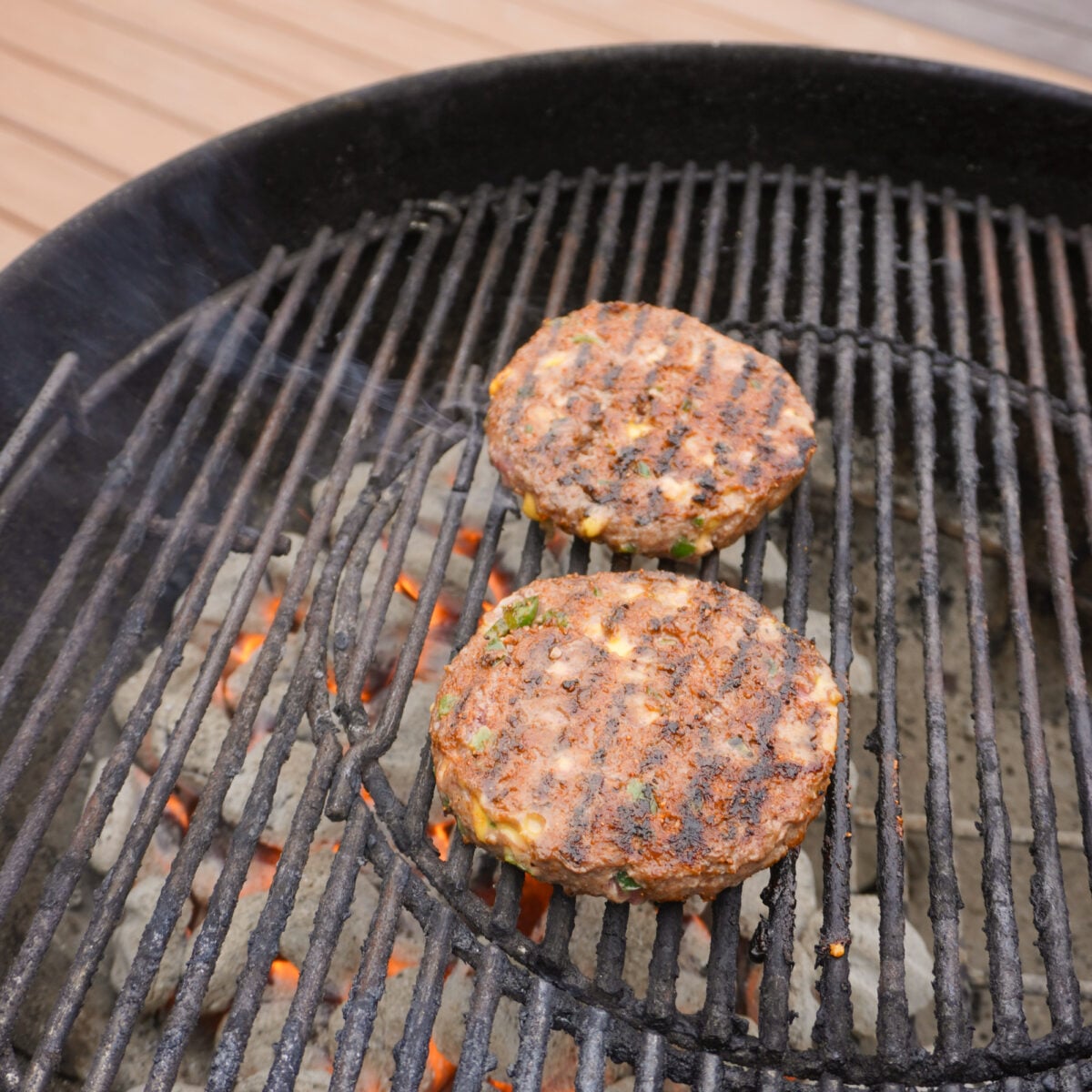 grilled jalapeno beef patties on a charcoal grill.