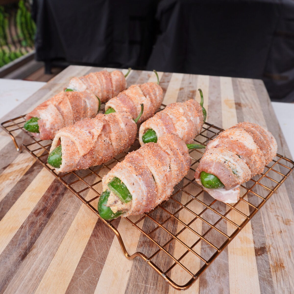 seasoned and bacon wrapped jalapeno poppers on a wire rack.