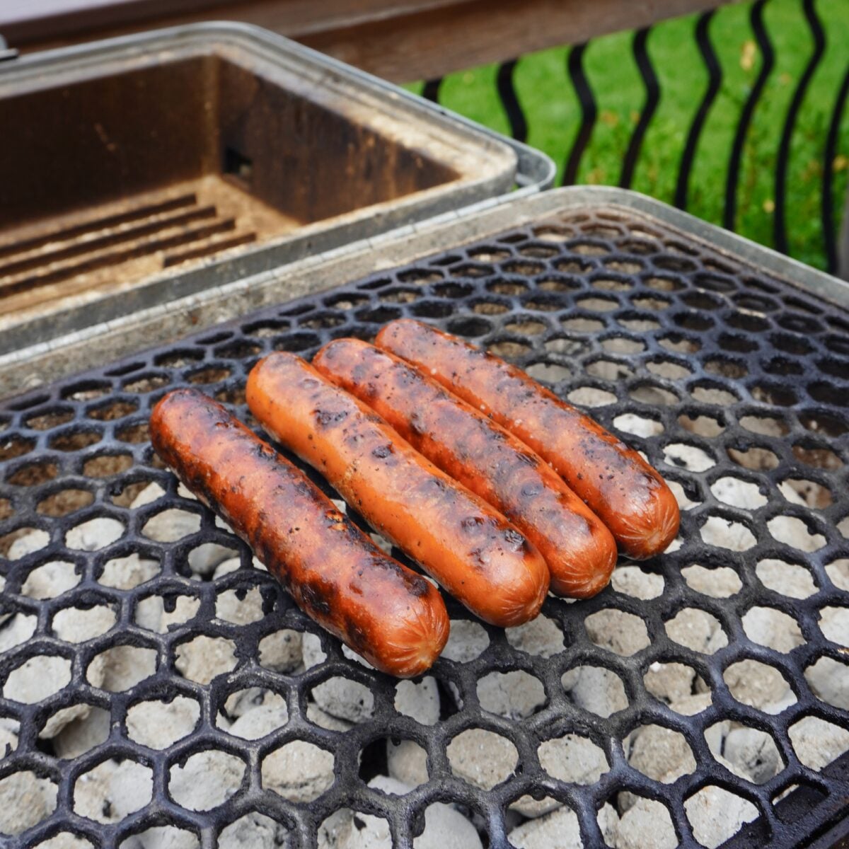 Grilled hotdogs over a charcoal grill.