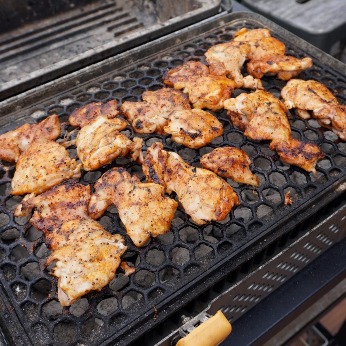 Grilled chicken thighs on a charcoal grill.