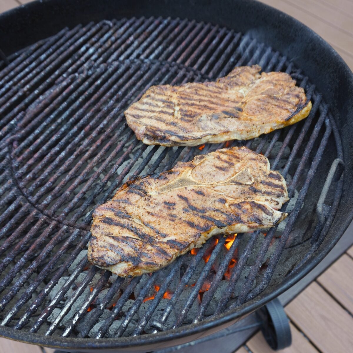 Grilled Savory Pork steaks over direct heat on a Weber Kettle Grill.