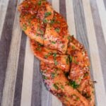 Smoked braided salmon on the cutting board topped with chives.