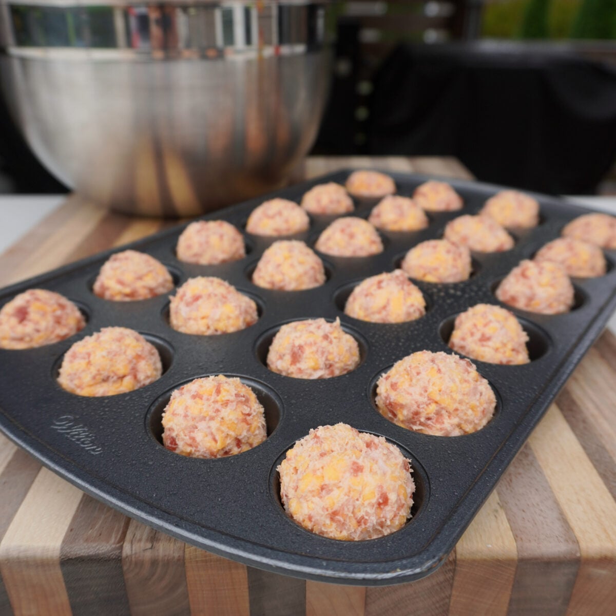 round raw sausage balls in mini muffin pan.