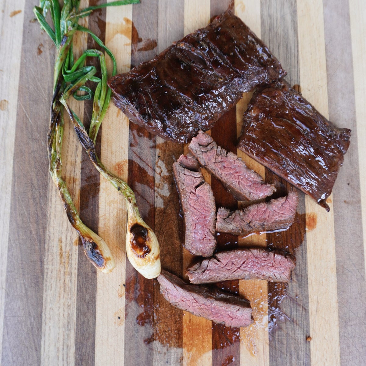 Marinated Skirt Steak sliced with grilled onion next to it.