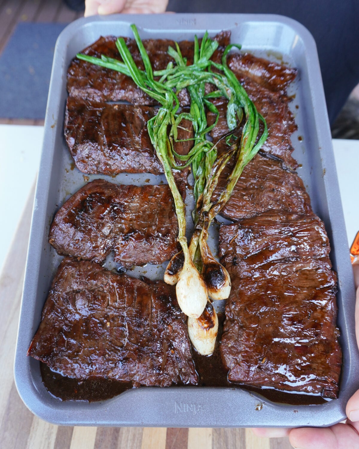 Marinated Skirt Steak with grilled onion on tray.